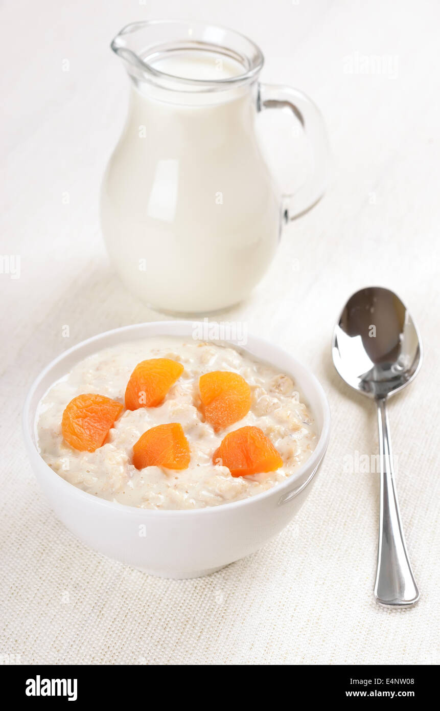 Oatmeal porridge with dried apricots and jug of milk Stock Photo
