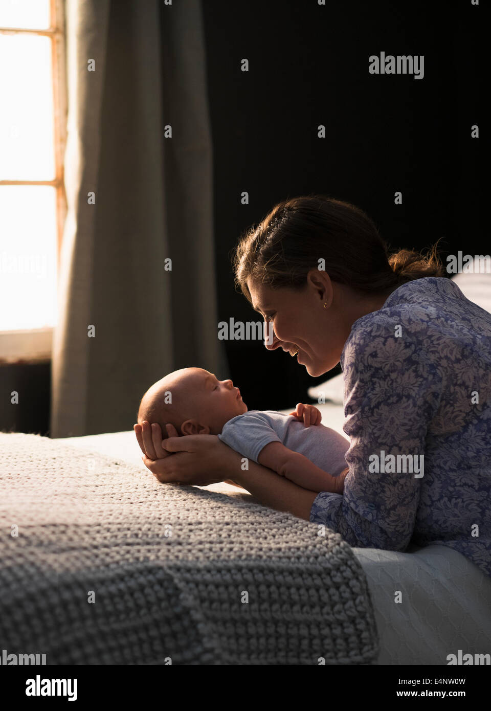 Mother holding baby boy (2-5 months) in bedroom Stock Photo