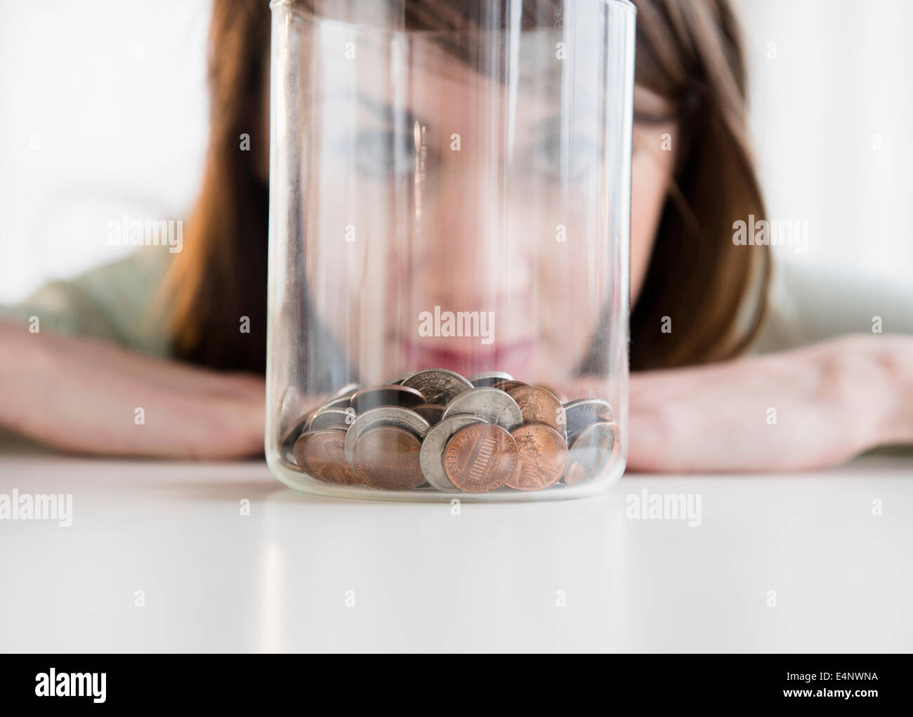 Young woman looking at coins in jar Stock Photo