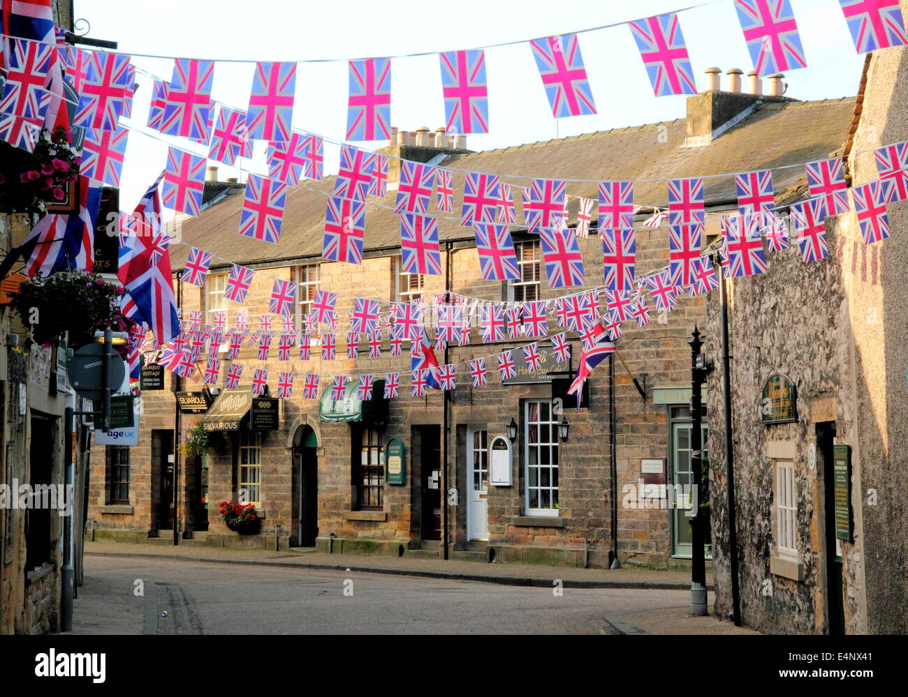 Union Jack bunting flying above a town centre shopping street in Bakewell; an historic English market town - summer, UK Stock Photo