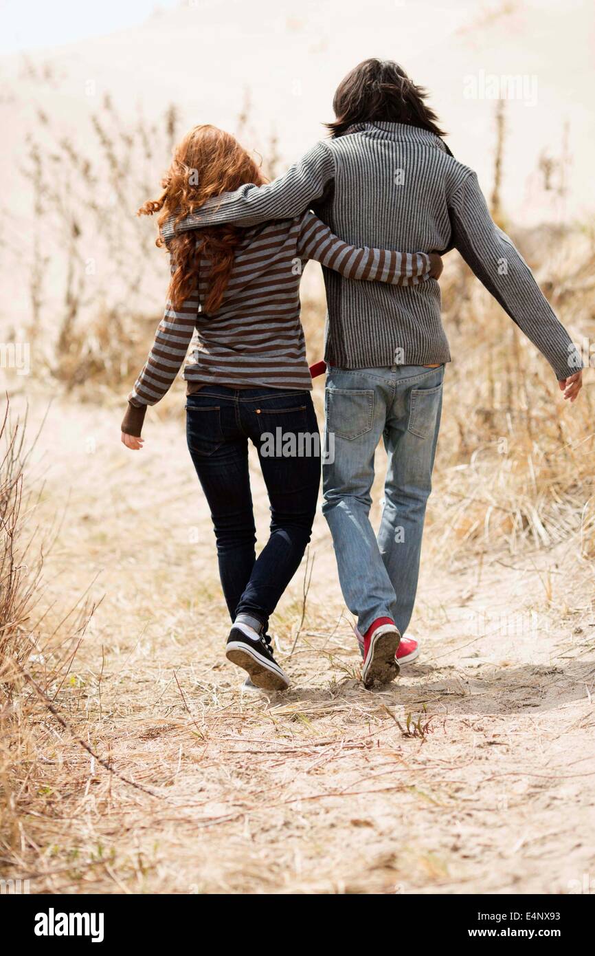 Rear view of couple walking on dirt road Stock Photo