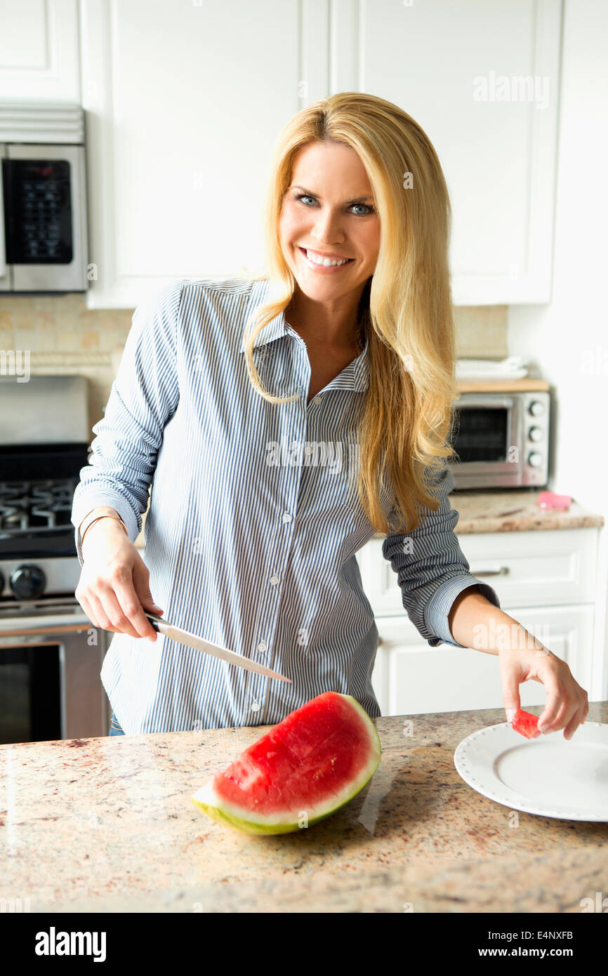 Blonde housewife cutting watermelon Stock Photo