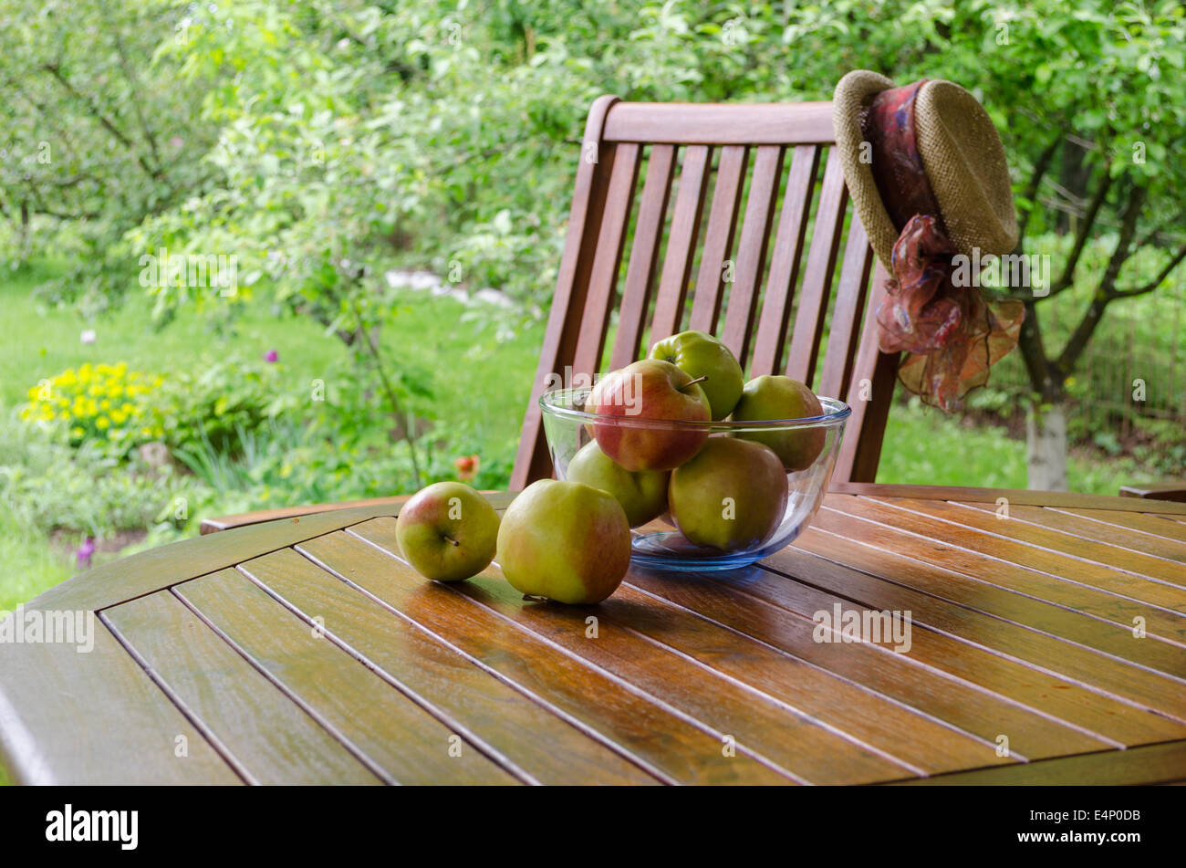 Apple tree fruits in glass dish on bower table in garden. Stock Photo