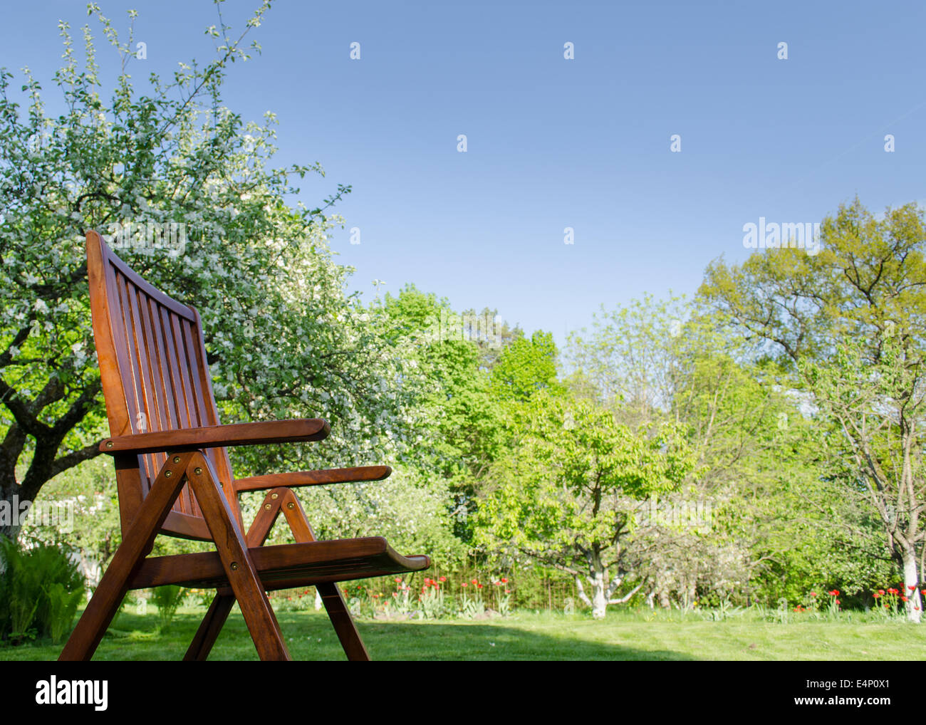 brown wooden garden chair outdoors on spring garden tree background Stock Photo