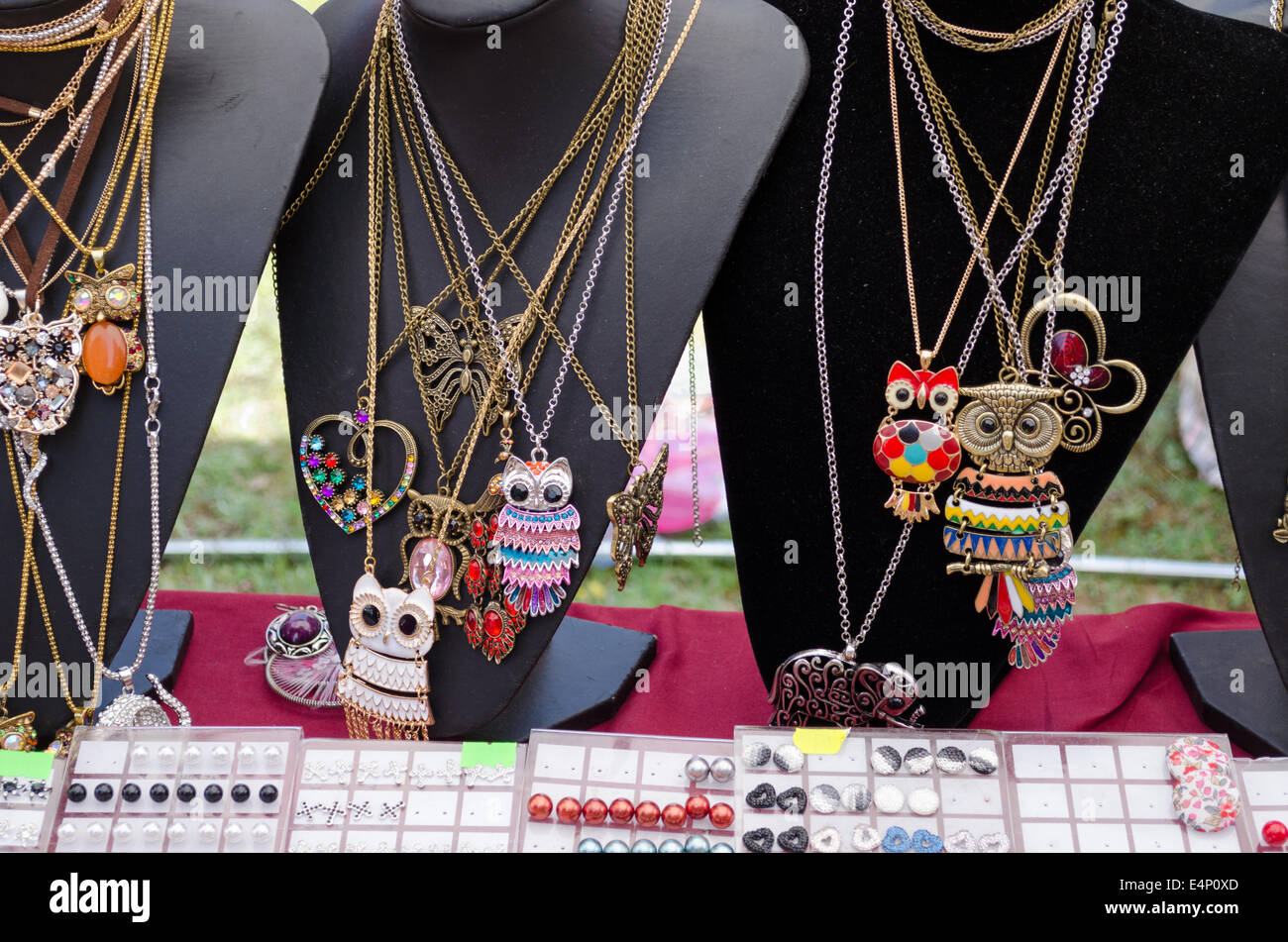 female owl shaped pendant necklaces and other decorations on three black stand city market Stock Photo