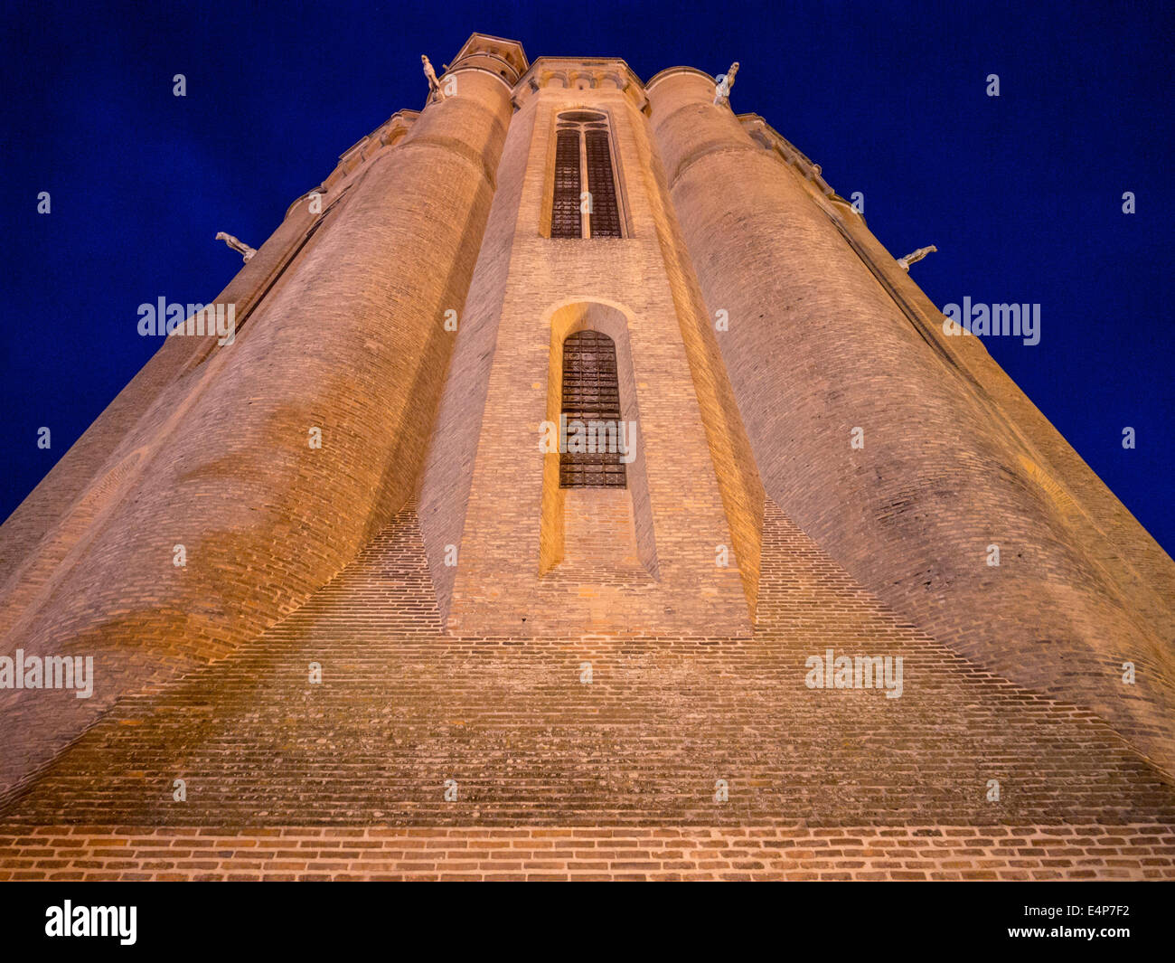 Imposing Main Tower of Albi's Cathedral. A night, floodlit view of the tower of the brick Cathedral in Albi. Gargoyles smile. Stock Photo