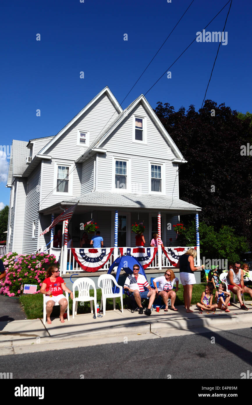 Spectators sitting outside decorated porch of house enjoying 4th of July Independence Day parades, Catonsville, Maryland, USA Stock Photo