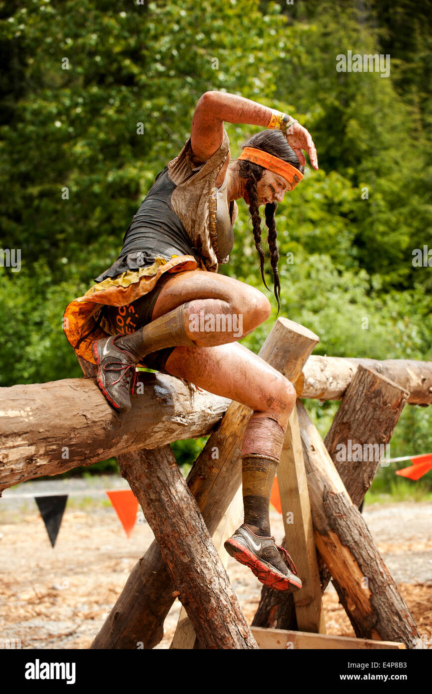 A mud covered woman vaults an obstacle at the Whistler Vancouver Tough Mudder event. Stock Photo