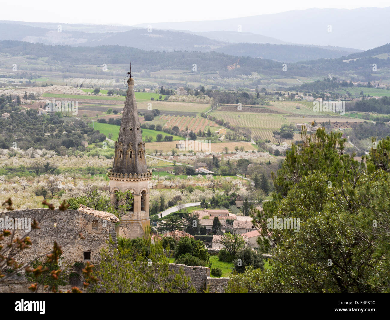 Church steeple in St-Saturnin-les -Apt. Tower of the lower village church with the valley farms, orchards and vineyards below Stock Photo
