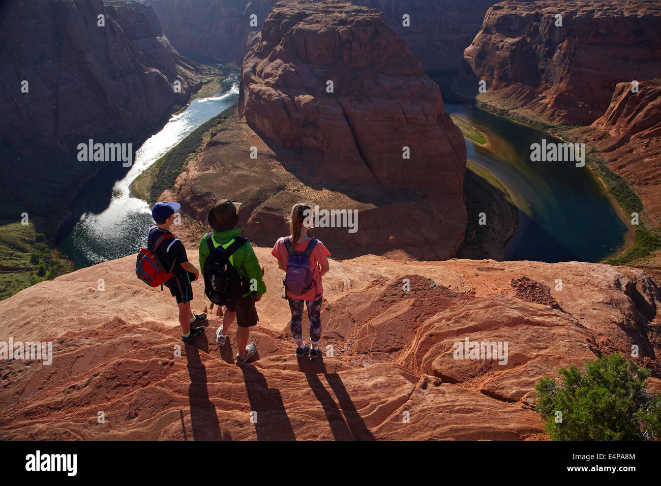 Tourists looking at 1000 ft drop down to Colorado River at Horseshoe Bend, just outside Grand Canyon, near Page, Arizona, USA Stock Photo
