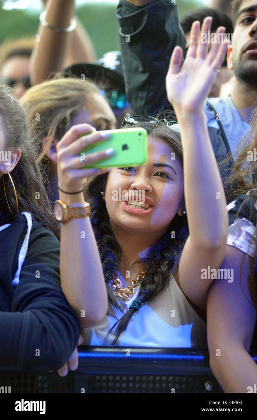 A YOUNG WOMAN WATCHING BANDS AT A OUTDOOR MUSIC  FESTIVAL AND FILMING ON MOBILE  PHONE RE FESTIVALS ROCK SINGERS TEENAGERS  UK Stock Photo