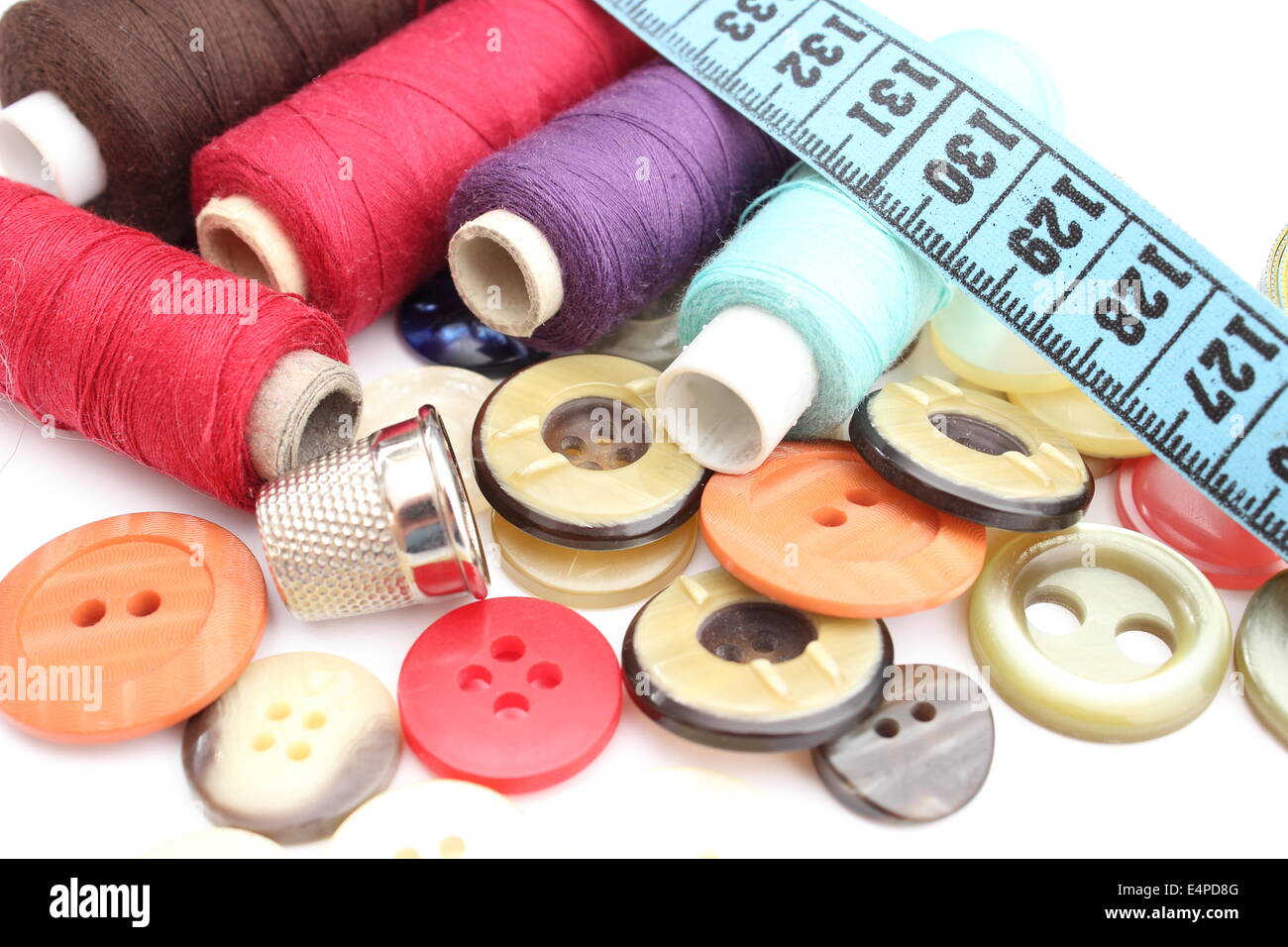 Colorful spools of thread with a tape measure, thimble and buttons ...