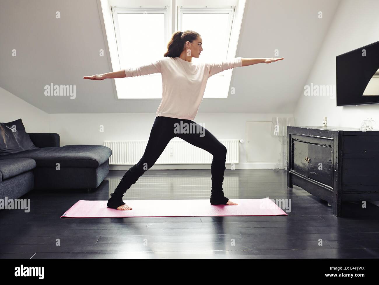 Portrait of a young woman doing yoga on an exercising mat in her living ...