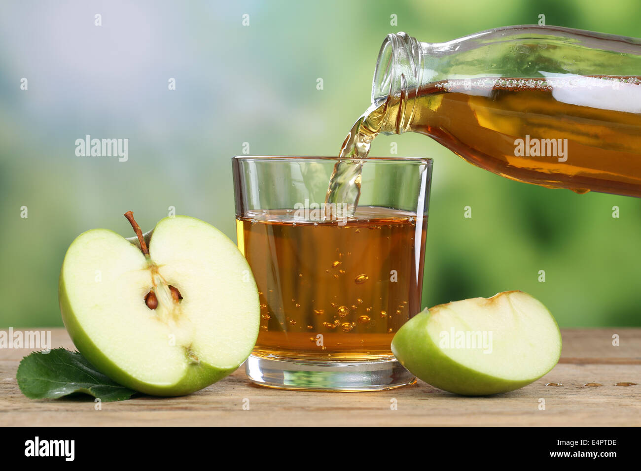 Apple juice pouring from green apples fruits in summer into a glass Stock Photo