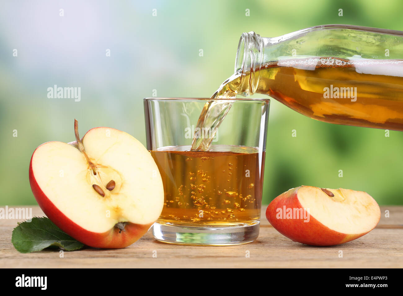 Apple juice pouring from red apples fruits in summer into a glass Stock Photo