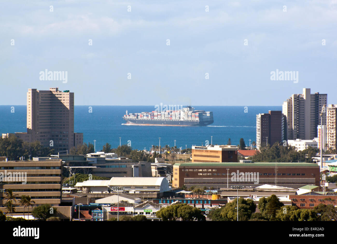 DURBAN, SOUTH AFRICA - JULY 10, 2014: Large container ship leaves harbor behind city skyline in Durban, South Africa Stock Photo