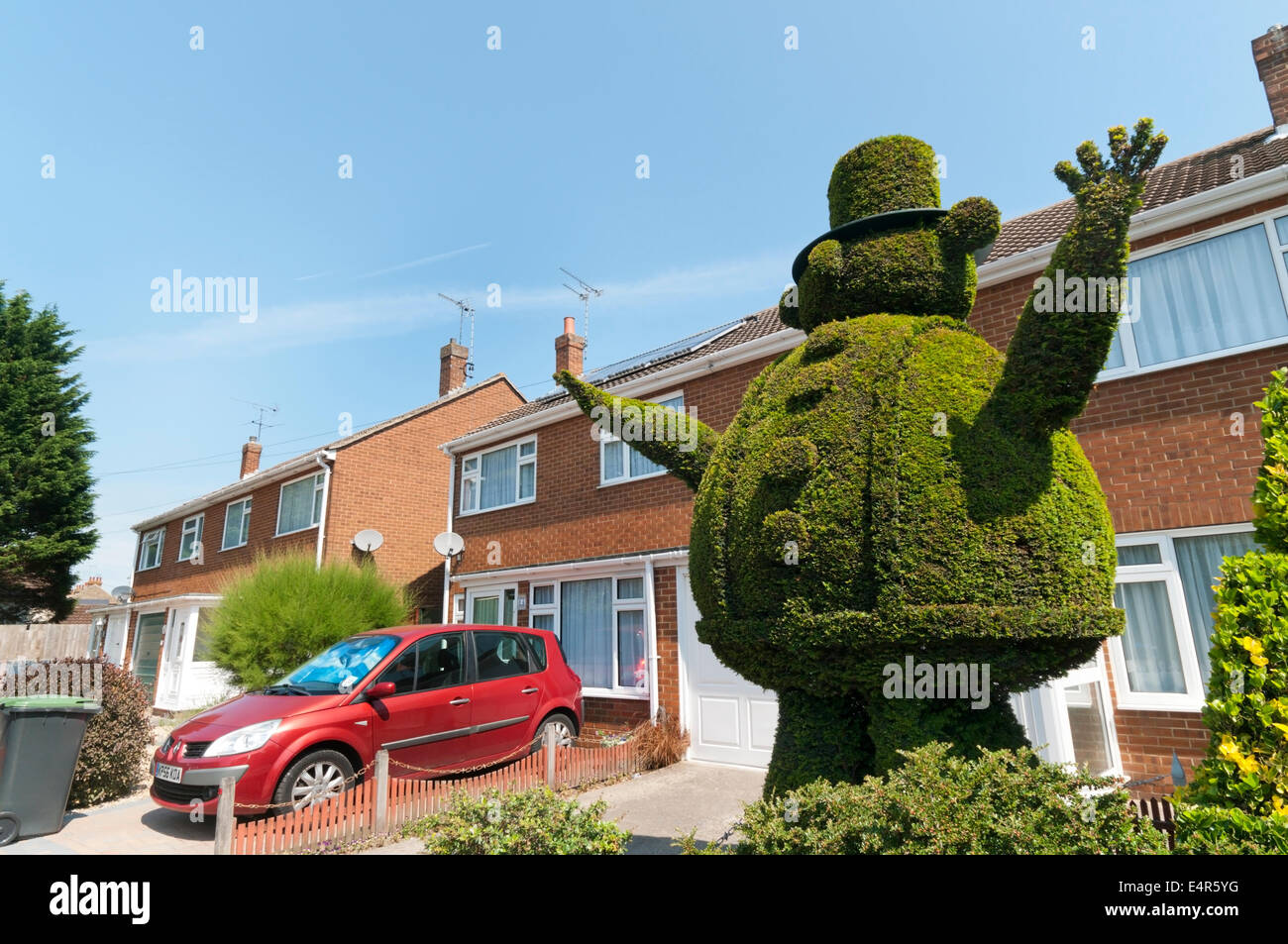 Topiary work of a large fat man in a hat in the front garden of a house in Broadstairs. Stock Photo