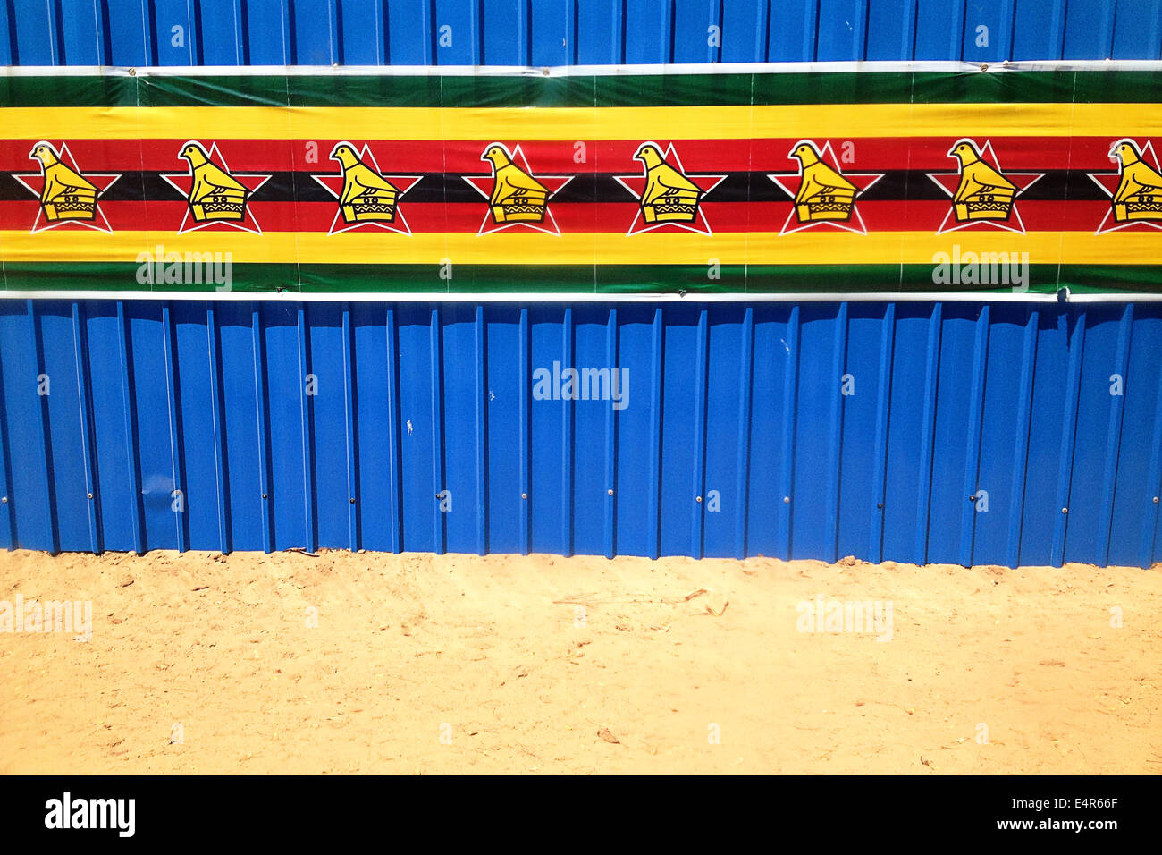 Zimbabwe flag banner along a blue corrugated wall Stock Photo