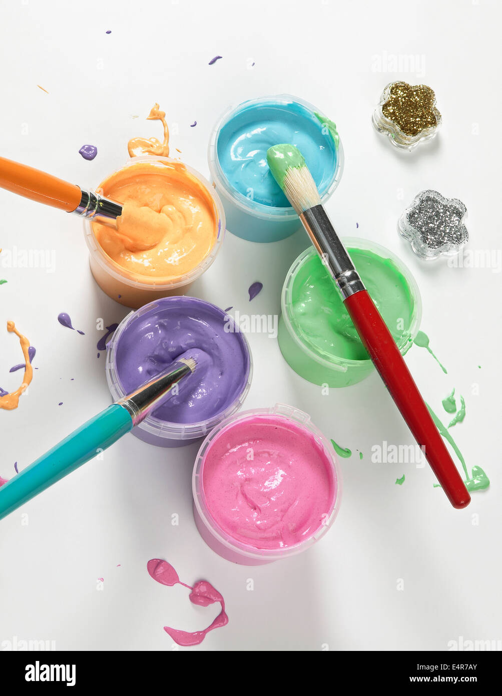 Pots of colourful paints, paintbrushes, and glitter Stock Photo