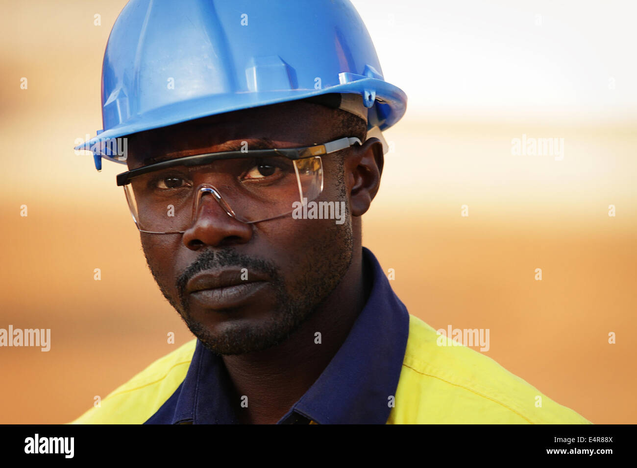 Portrait of a young Zambian man in blue hard hat and safety goggles. Stock Photo