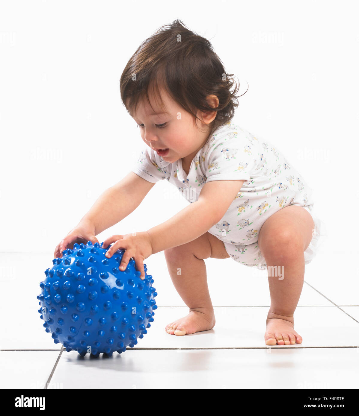 Young boy playing with spiky blue ball Stock Photo