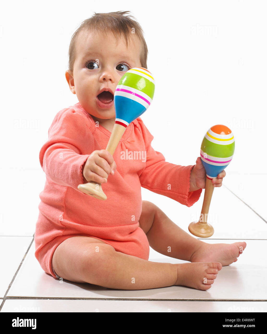 Baby girl (8 months) with maraca in each hand Stock Photo