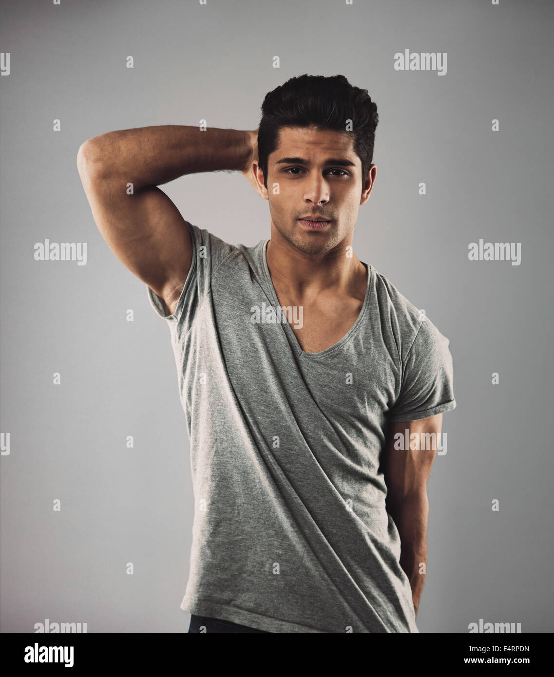 Portrait of handsome young man posing against grey background. Hispanic male fashion model looking at camera. Stock Photo