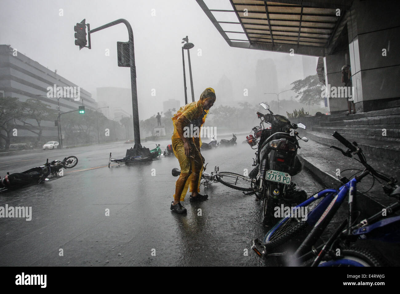 Manila, Philippines. 16th July, 2014. Makati City, Philippines - A man attempts to gain his balance after losing control of his bicycle caused by strong winds as Typhoon Rammasun hit Metro Manila on July 16, 2014. Typhoon Rammasun (locally known as Glenda) had maximum sustained winds of 150 kph and gustiness of up to 185 kph when it hit Metro Manila. Across the country, about 400,000 people had fled their homes and sheltered in evacuation centers, according to the disaster management council. Credit:  ZUMA Press, Inc./Alamy Live News Stock Photo