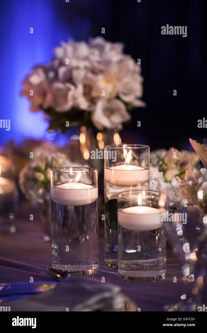 Close-up of floating candles in glass candle holders on table at reception,  with flower arrangements in background, Canada Stock Photo - Alamy