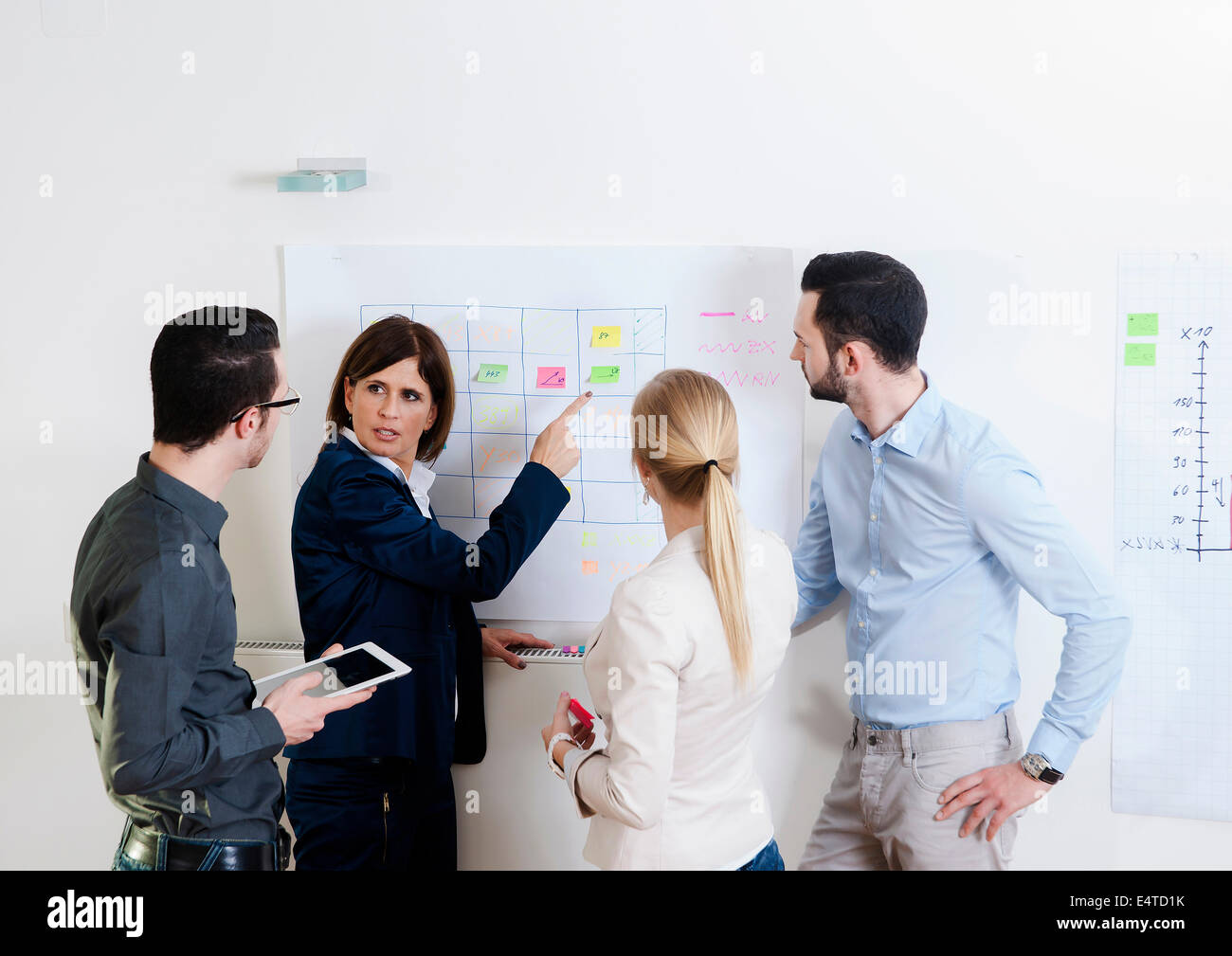 Group of young business people and mature businesswoman in discussion in office, Germany Stock Photo