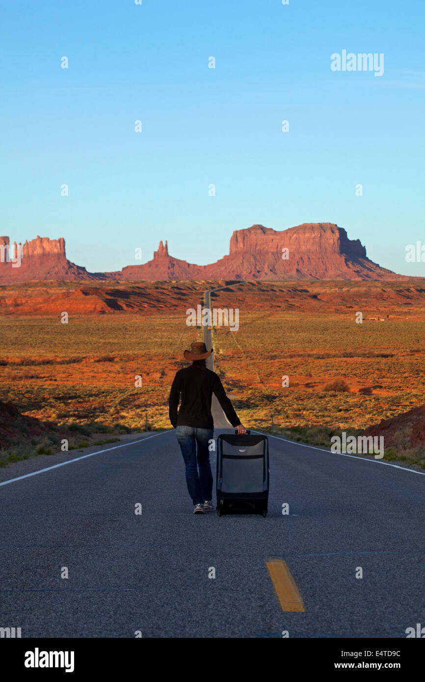 Woman with suitcase on U.S. Route 163 heading towards Monument Valley, Navajo Nation, Utah, near Arizona Border, USA Stock Photo