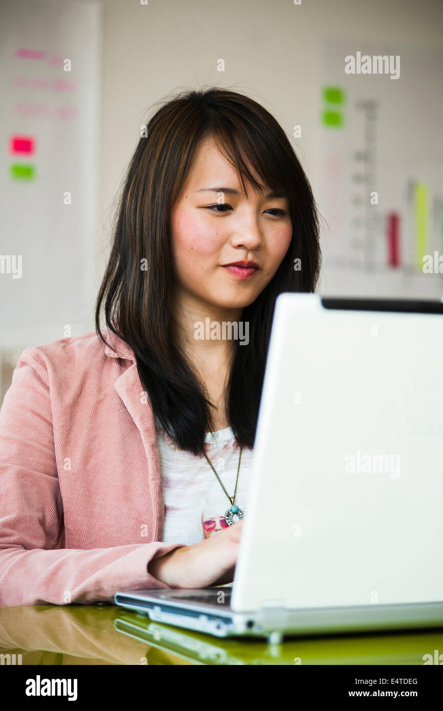 Young woman working on laptop computer in office, Germany Stock Photo