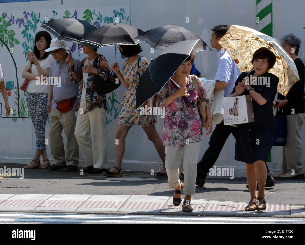 Tokyo, Japan. 16th July, 2014. A parasol is a must item for a woman as an  early summer heat bakes Tokyo with the temperature soaring as high as  nearly 90 degrees Fahrenheit. ©