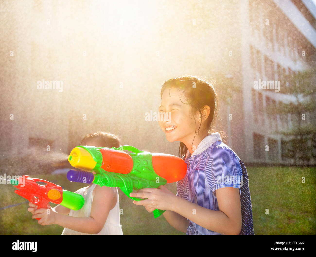 Cheerful girls playing water guns in the park Stock Photo
