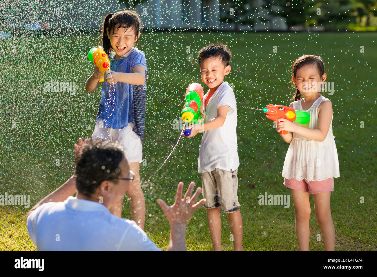 little guys using water guns to spray their father Stock Photo