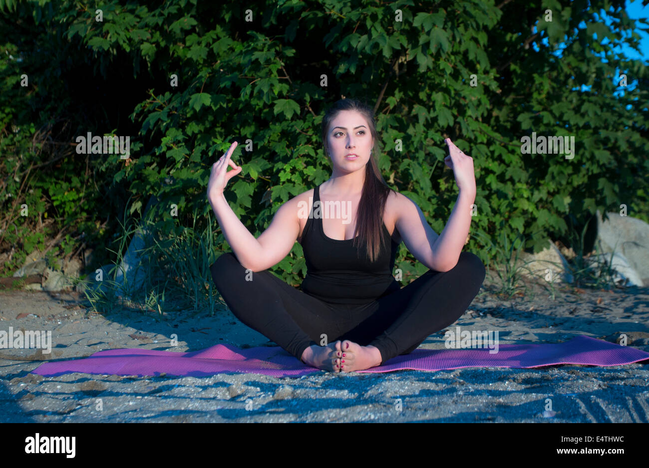 An attractive young woman meditates on the beach. Stock Photo