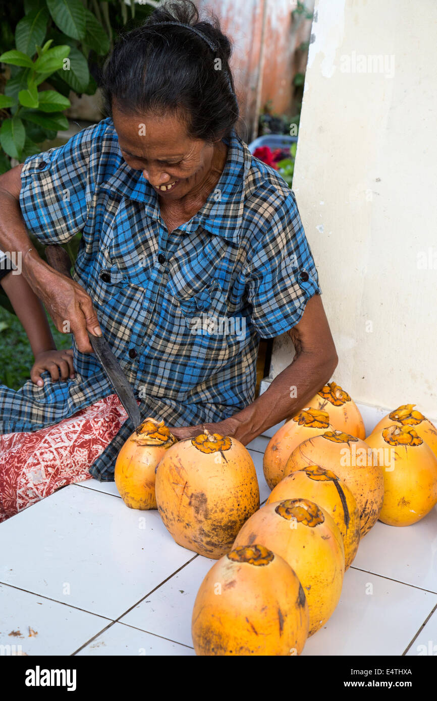 Bali, Indonesia.  Woman Opening a Fresh Coconut for Guests. Stock Photo