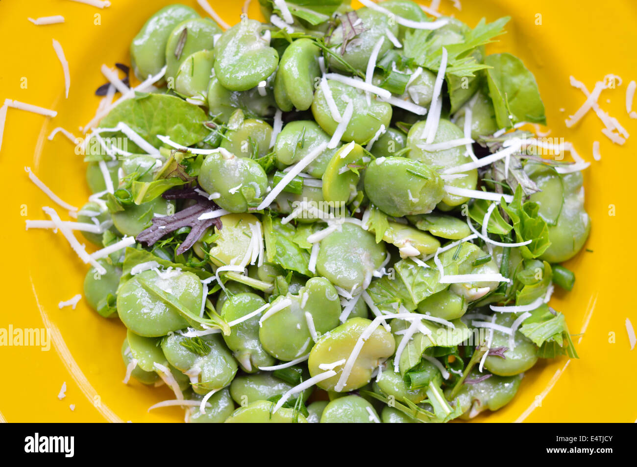 Close-up of green broad bean salad on yellow plate. Broad bean, young ...