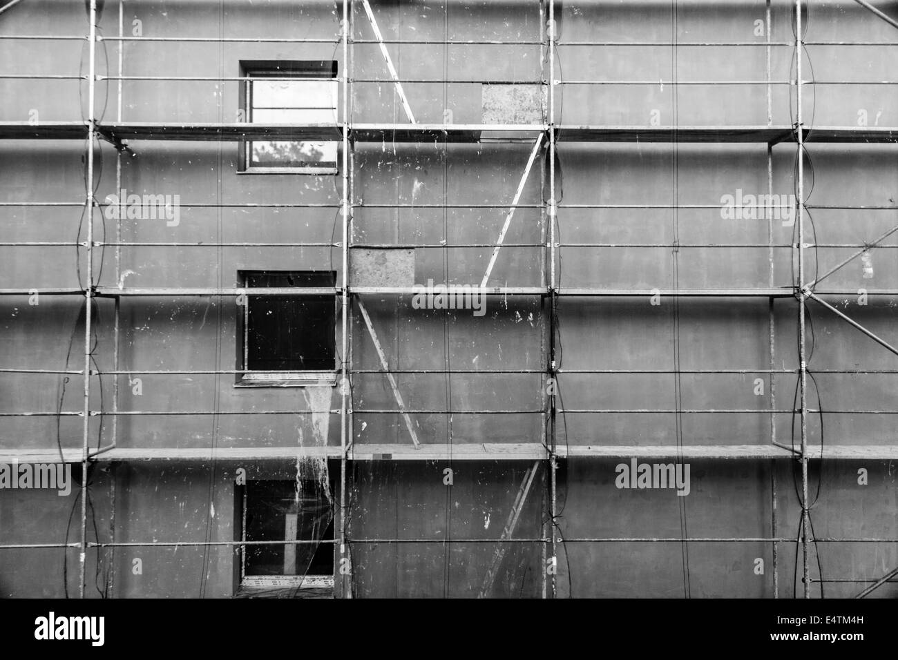 Scaffold on a block of flats in Czech Republic. 3 windows, 4 ladders & access hatches can be seen. All covered by a safety net Stock Photo