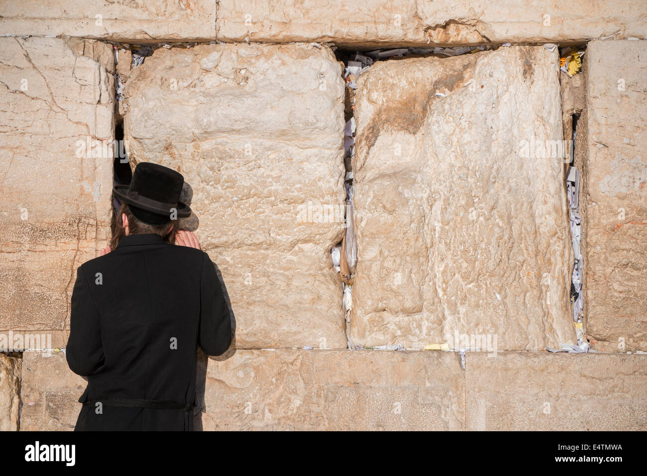 Jewish man prays next to a crack filled with letters containing written prayers at the Western Wall in Jerusalem. Israel Stock Photo