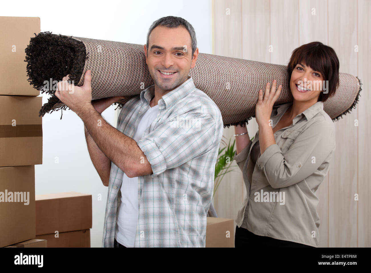 Couple carrying carpet over shoulders Stock Photo Alamy