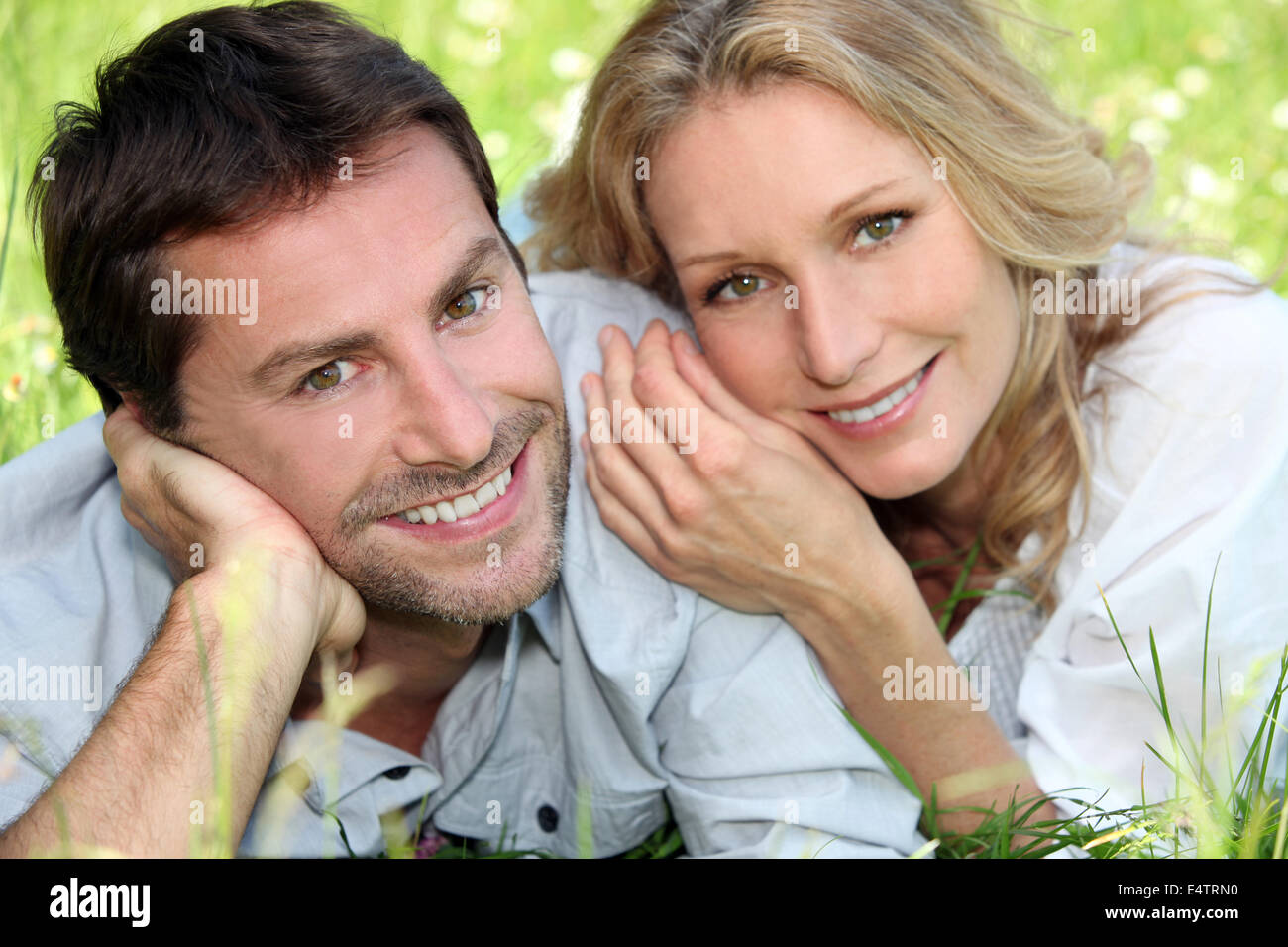 Happy couple lying on grass Stock Photo - Alamy