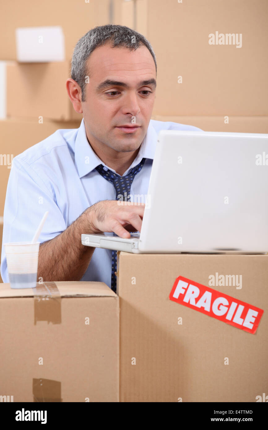 entrepreneur with laptop amid removal boxes Stock Photo