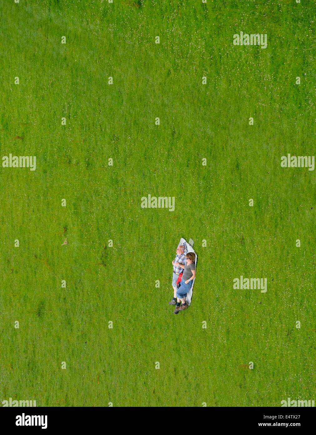A couple laying down sunbathing in a field. Image rotated to look like a wall of grass. Derbyshire england uk Stock Photo