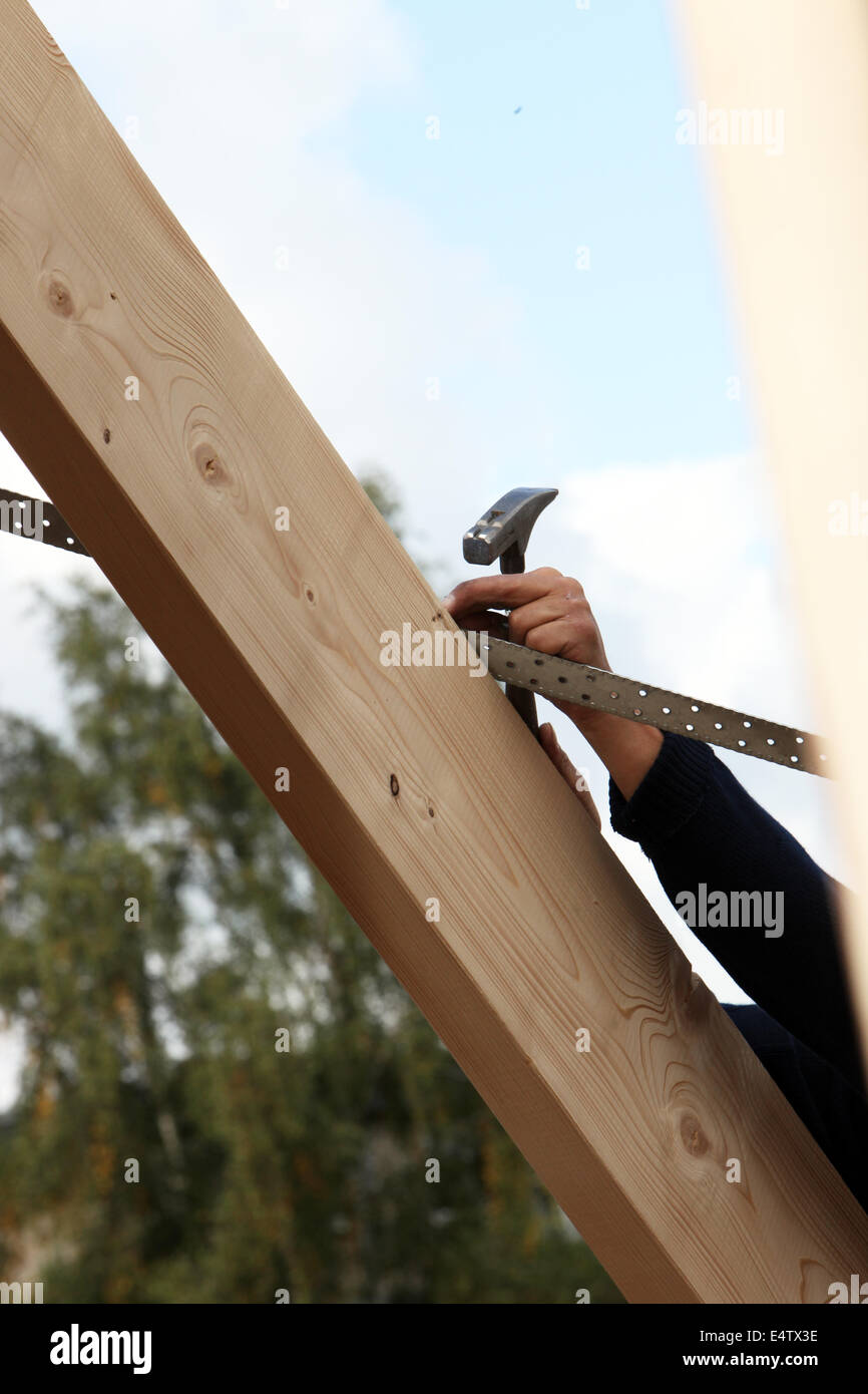 Man nailing a lath to a roof rafter Stock Photo