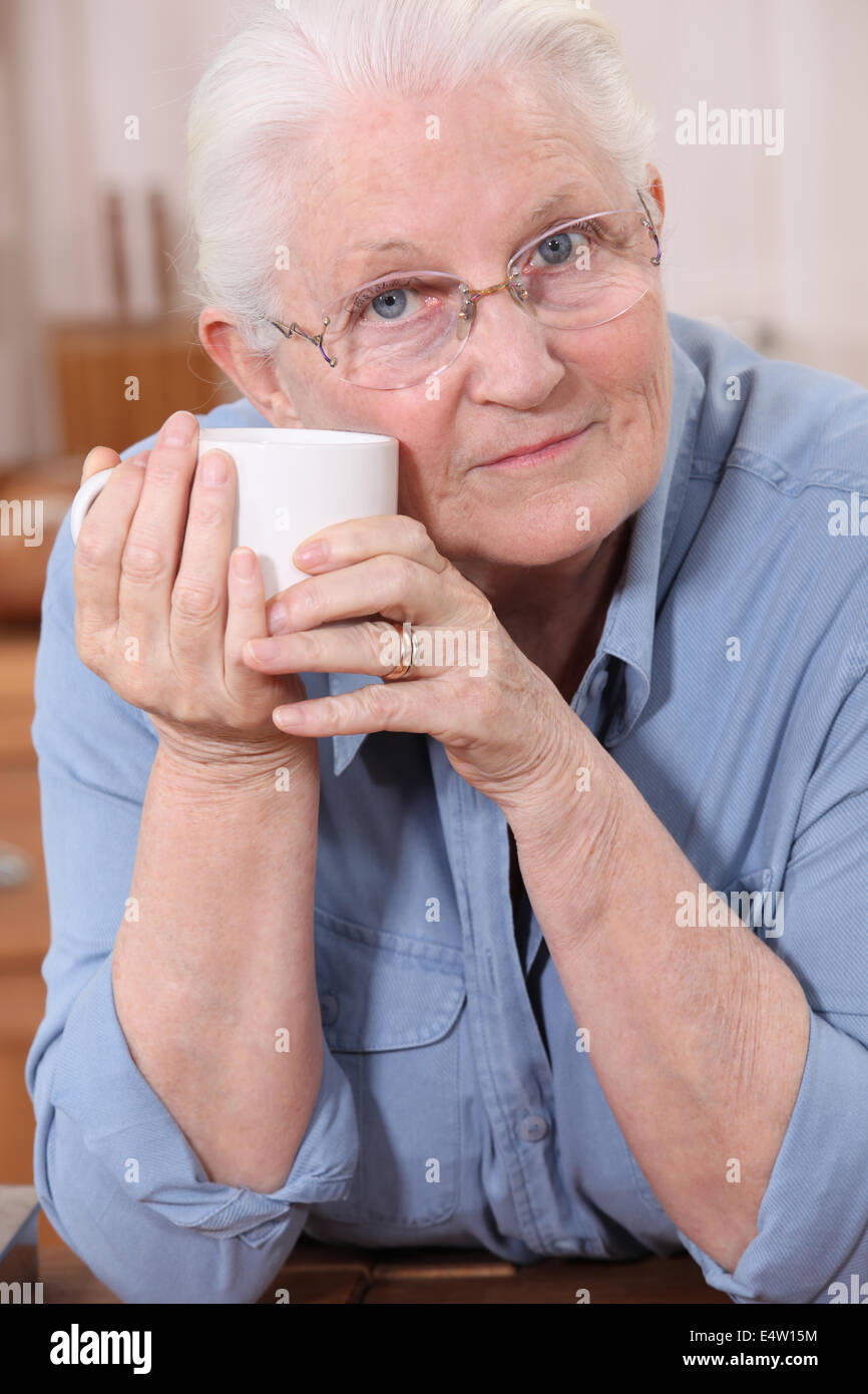 Old lady drinking from mug Stock Photo