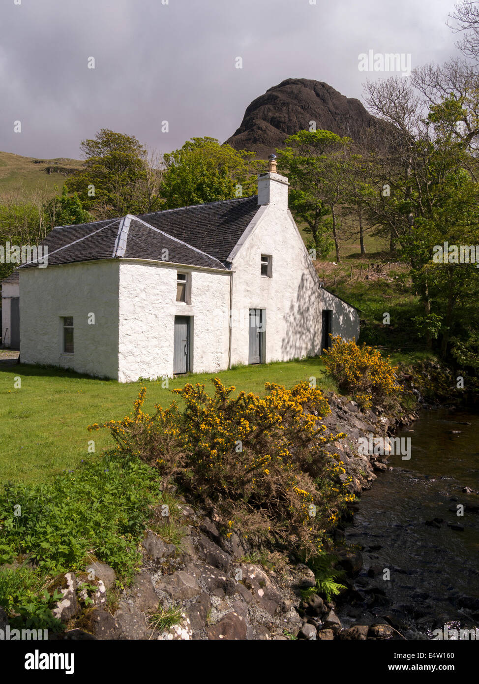 Sunlit white farm buildings at Talisker House in front of Pershal More mountain, Talisker, Isle of Skye, Scotland, UK Stock Photo