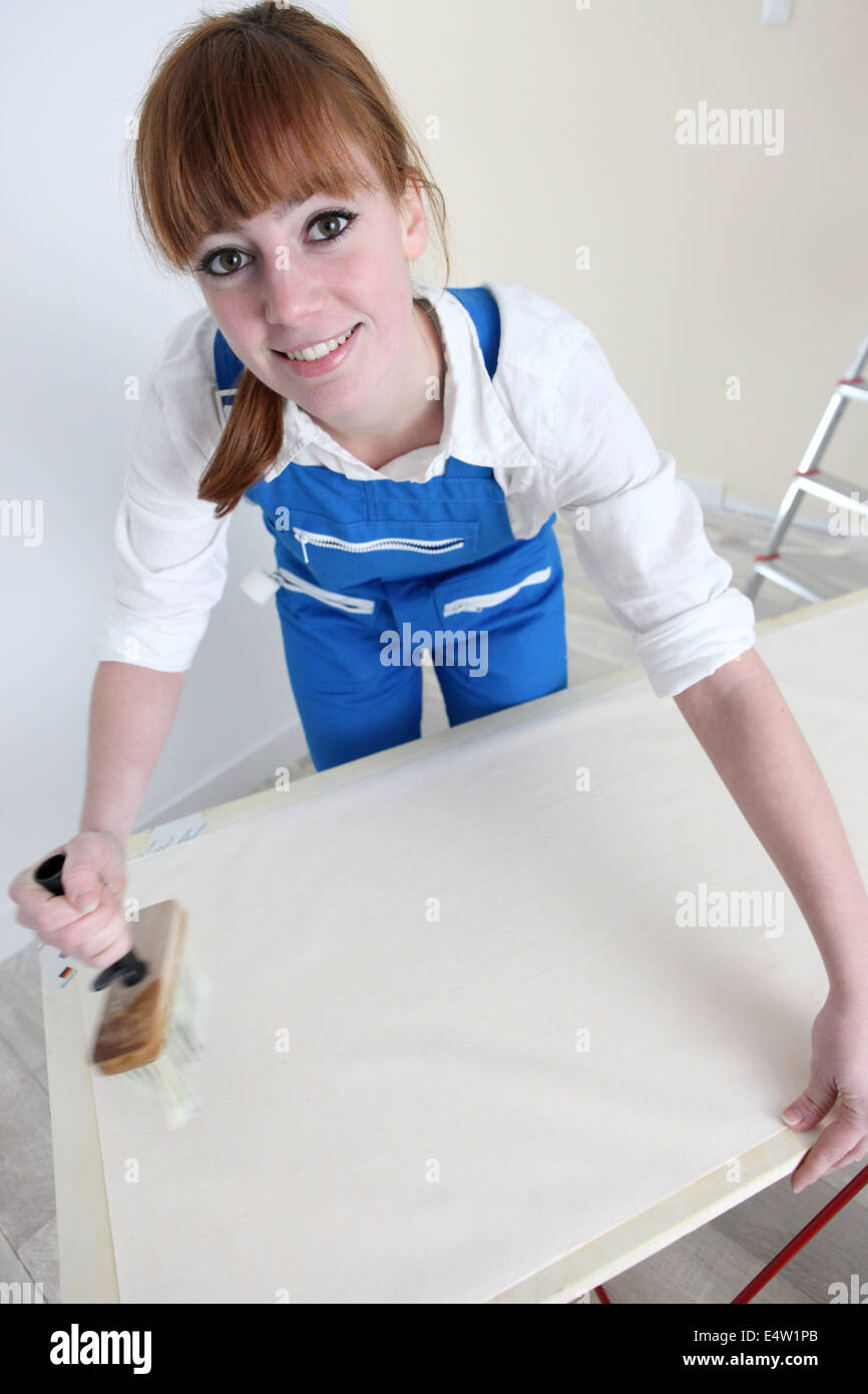 Woman gluing length of wallpaper Stock Photo