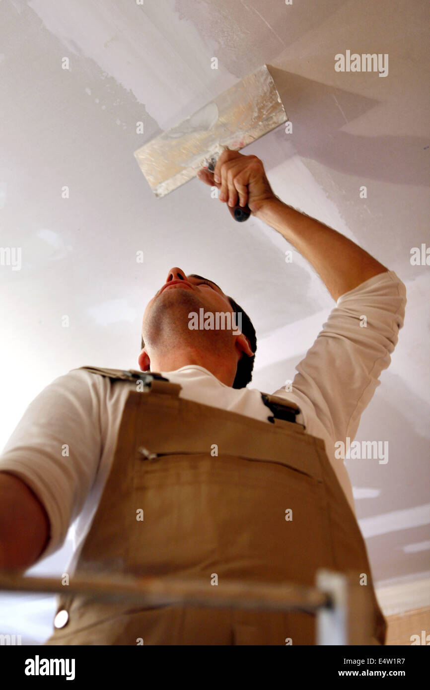 Man putting up a plasterboard ceiling Stock Photo