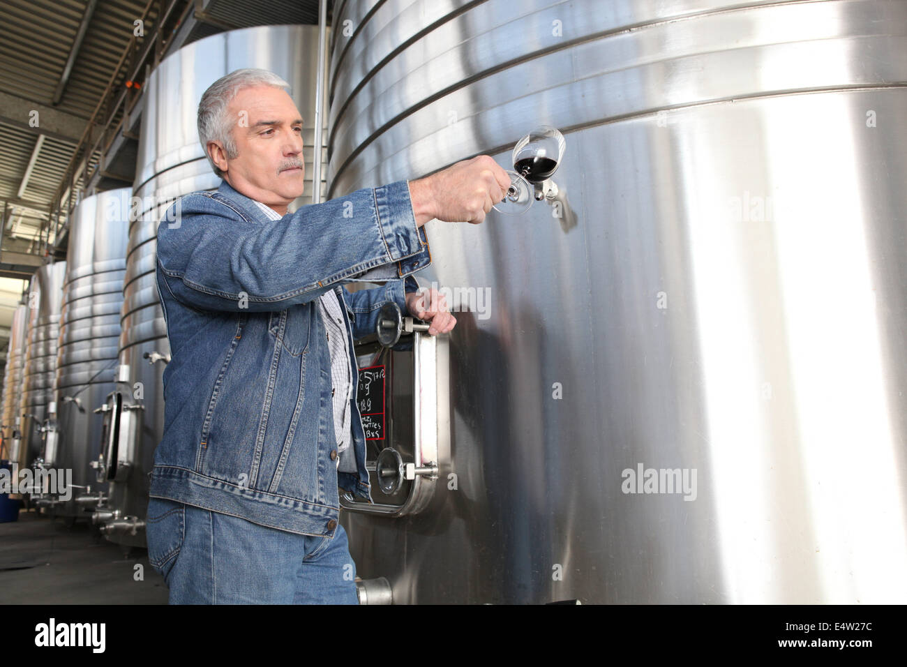Wine producer stood by tanks Stock Photo